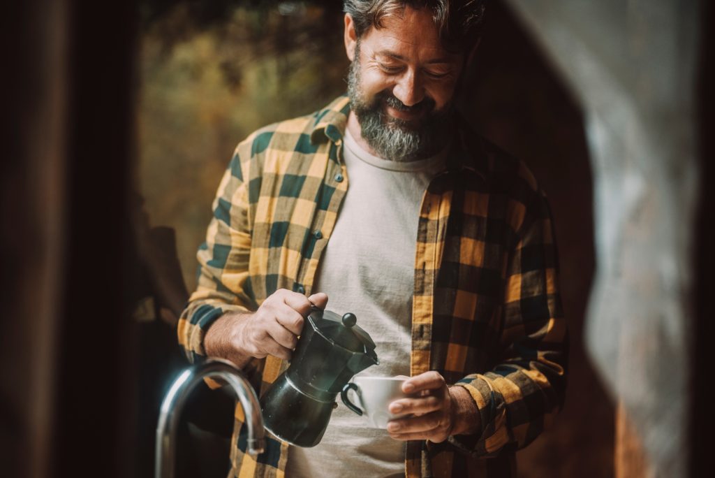 Mature man smile and drink italian style coffee espresso from aluminium moka. Concept of single
